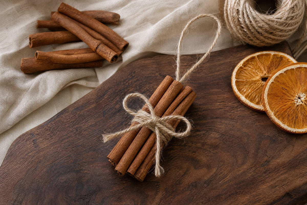Loose cinnamon sticks arranged beside a simple handmade cinnamon-stick ornament and natural craft materials, expressing the article's final invitation to