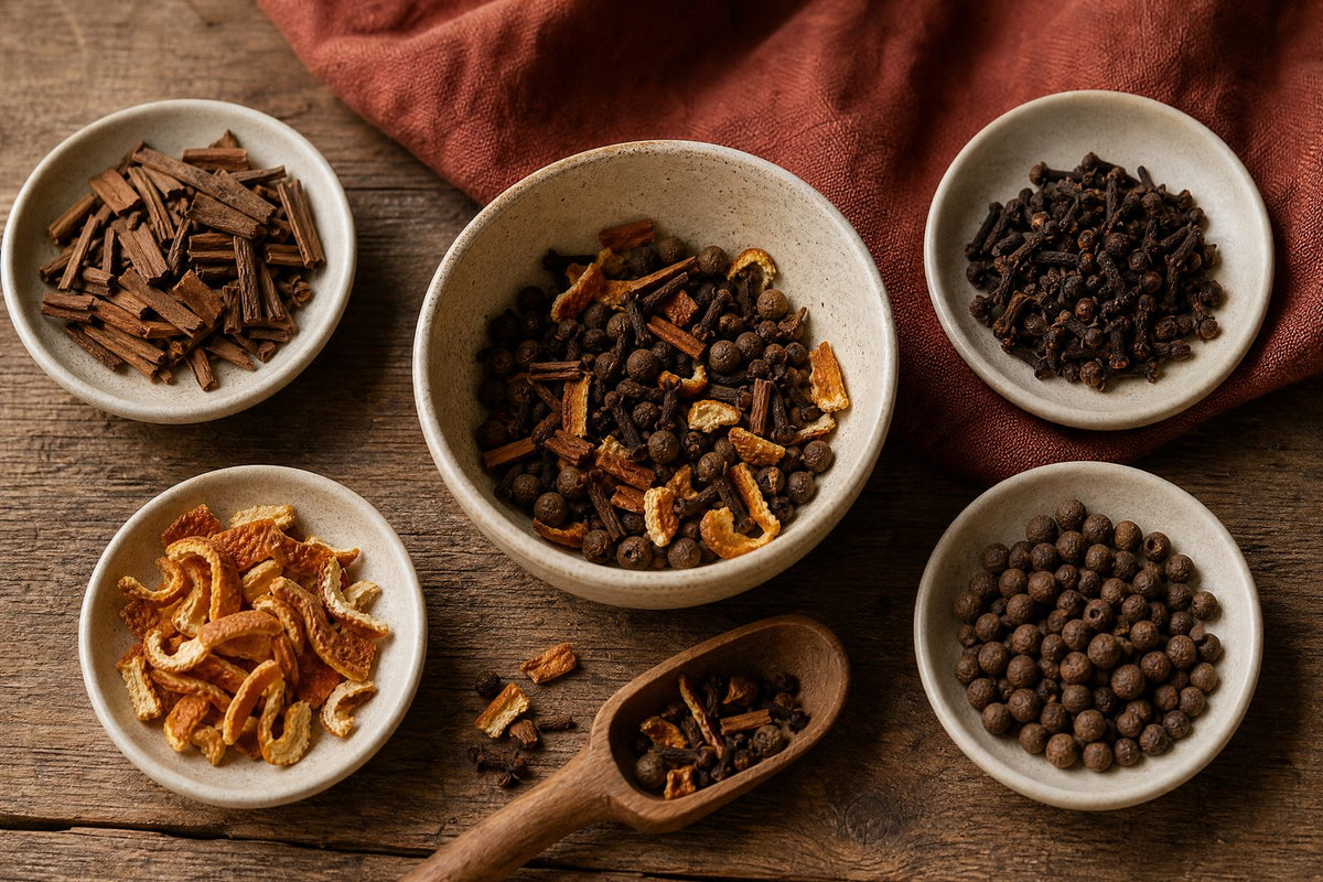 A home cook's customizable whole mulling-spice blend: separated cinnamon chips, whole cloves, allspice berries, and curls of dried orange peel being