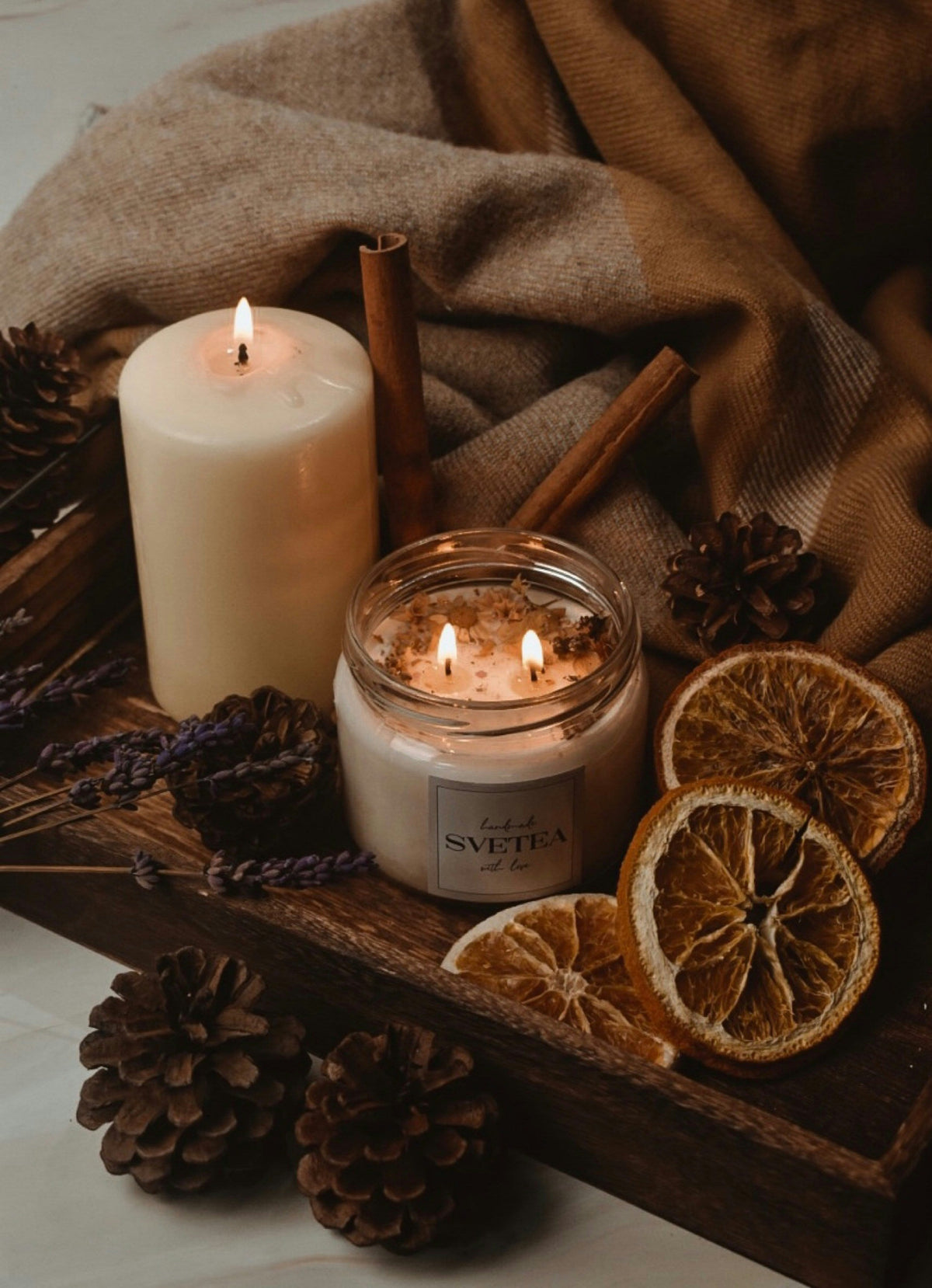 cinnamon scented candle with cinnamon next to it and dried oranges
